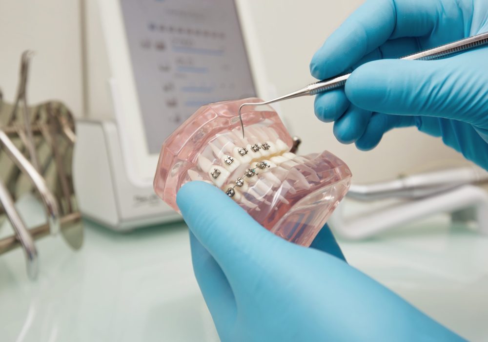 Prosthetics hands while working on the denture, false teeth, a study and a table with dental tools. Dental laboratory.